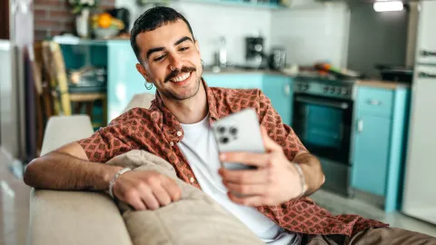 Mann sitz mit Handy auf Sofa | WINGS-Fernstudium